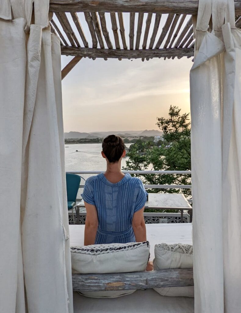 Girl sitting looking out on a sunset view of Lake Pichola in Udaipur.