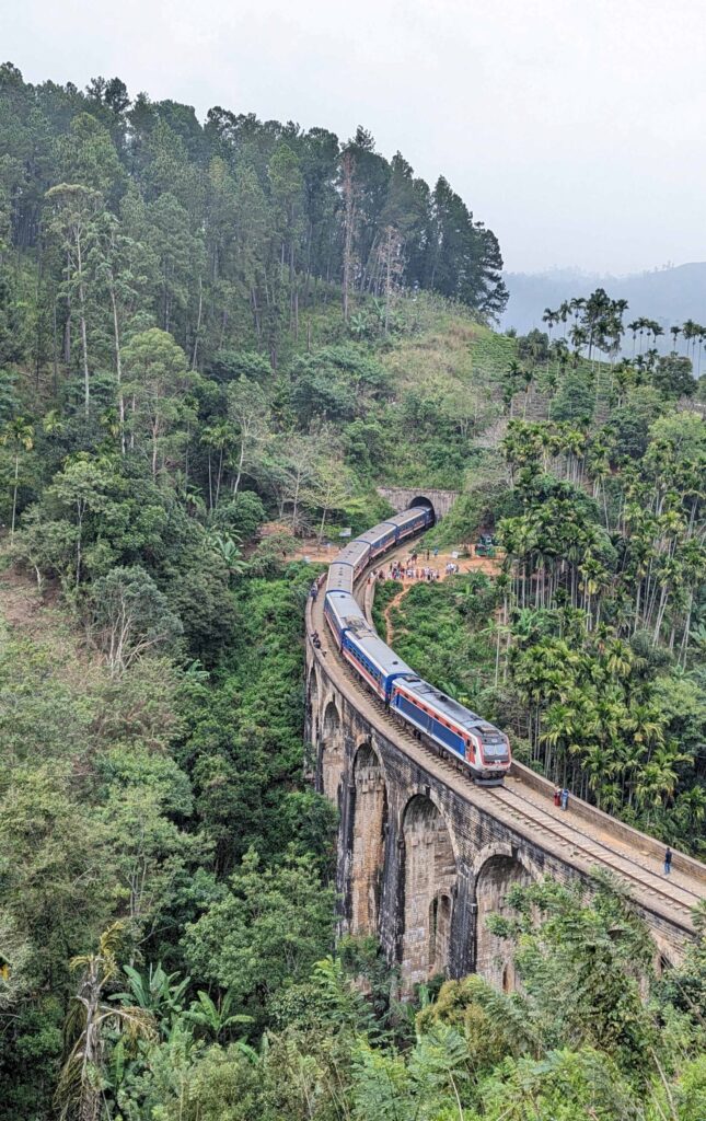 View of Nine Arches Bridge in Ella with a train crossing from a cafe on the hill.