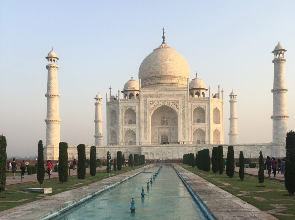 A view of the Taj Mahal from the gardens in front with a reflecting pool leading up to it. A must-see on any India Itinerary. 