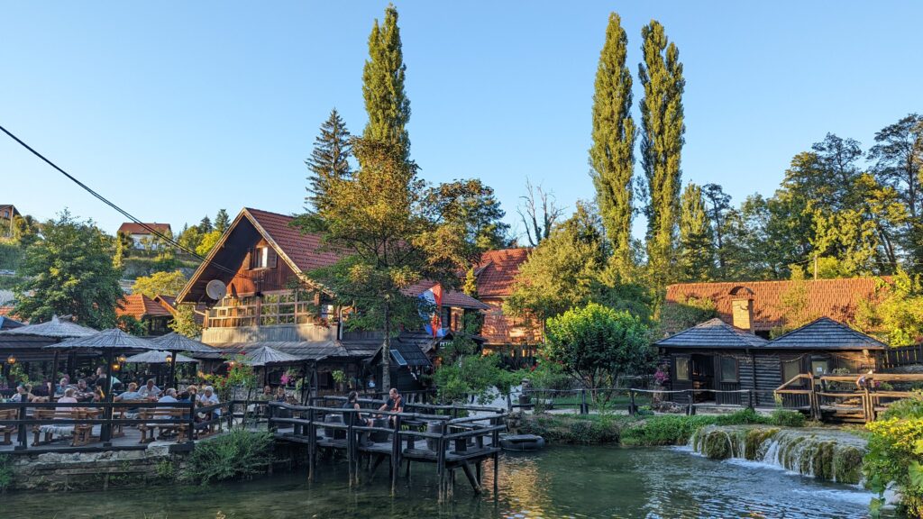 View of diners sitting on wooden platforms over a river at Petro restaurant in Rastoke, Croatia