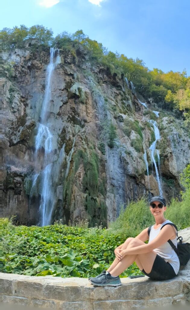 Girl sitting in front of Veliki Slap waterfall in Plitvice Lakes National Park