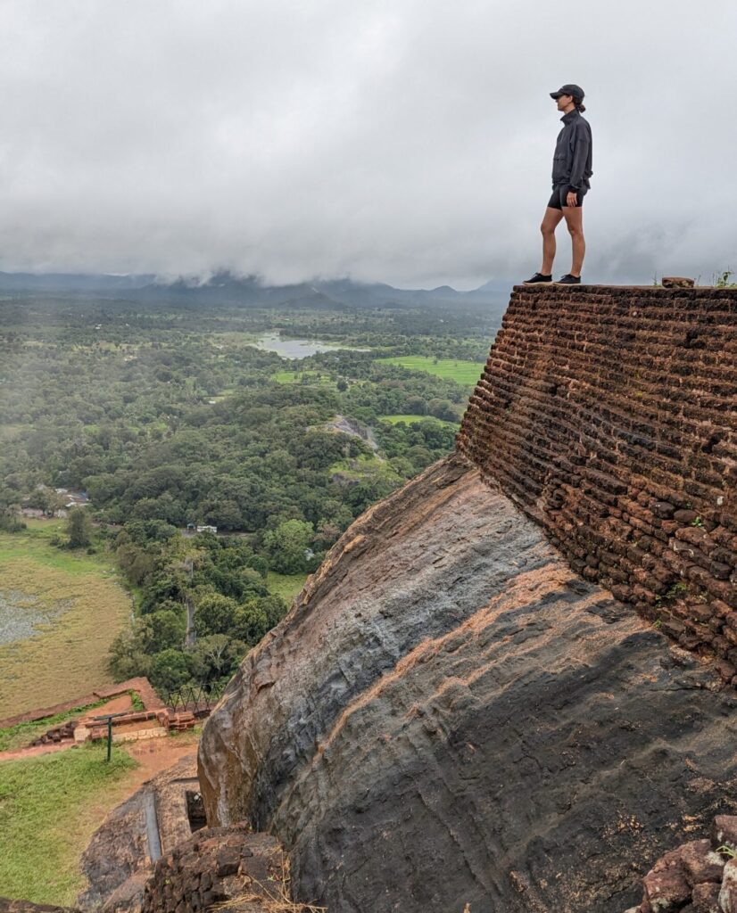 View from top of Sigiriya Rock with girl standing on the edge.