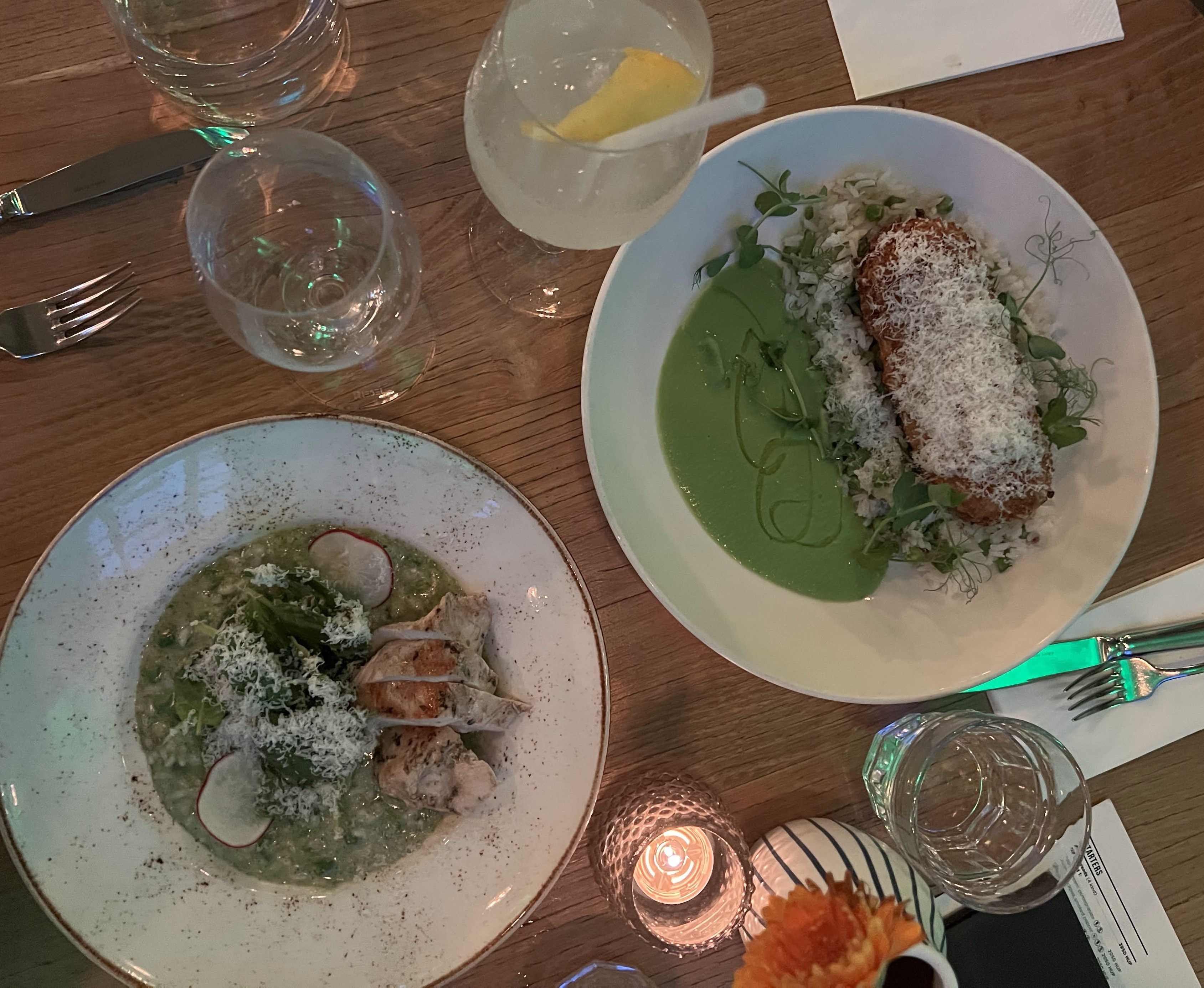 Overhead view of a table at Kiosk restaurant in Budapest with two plates with food and a couple cocktails.