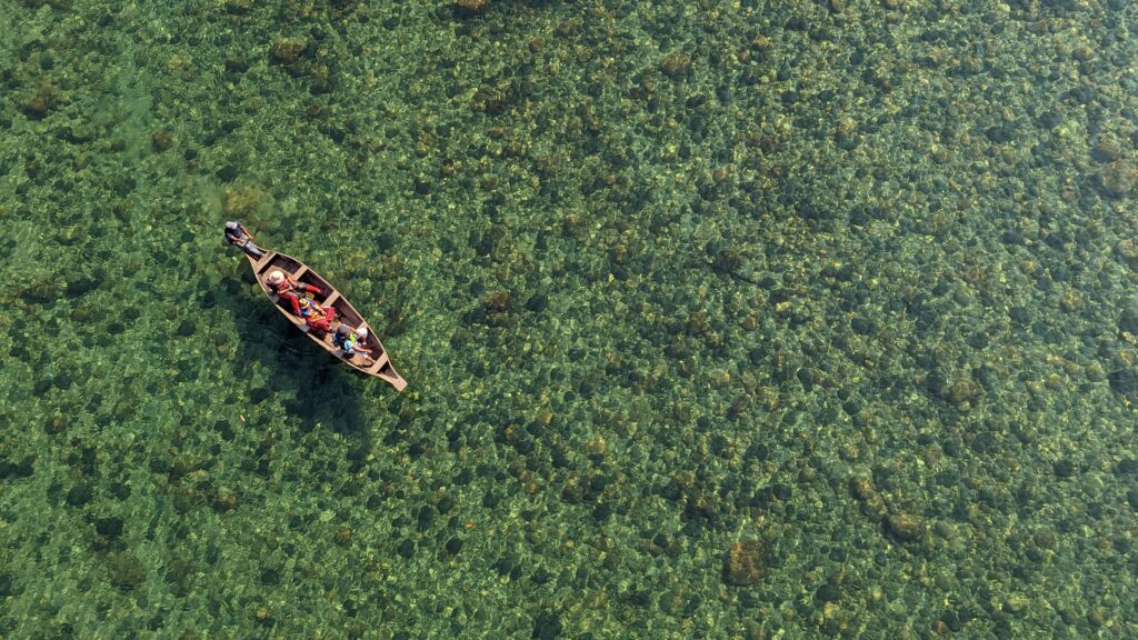 Overhead view of the Umngot River in Shnongpdeng with a single rowboat in the crystal clear water in Meghalaya India.