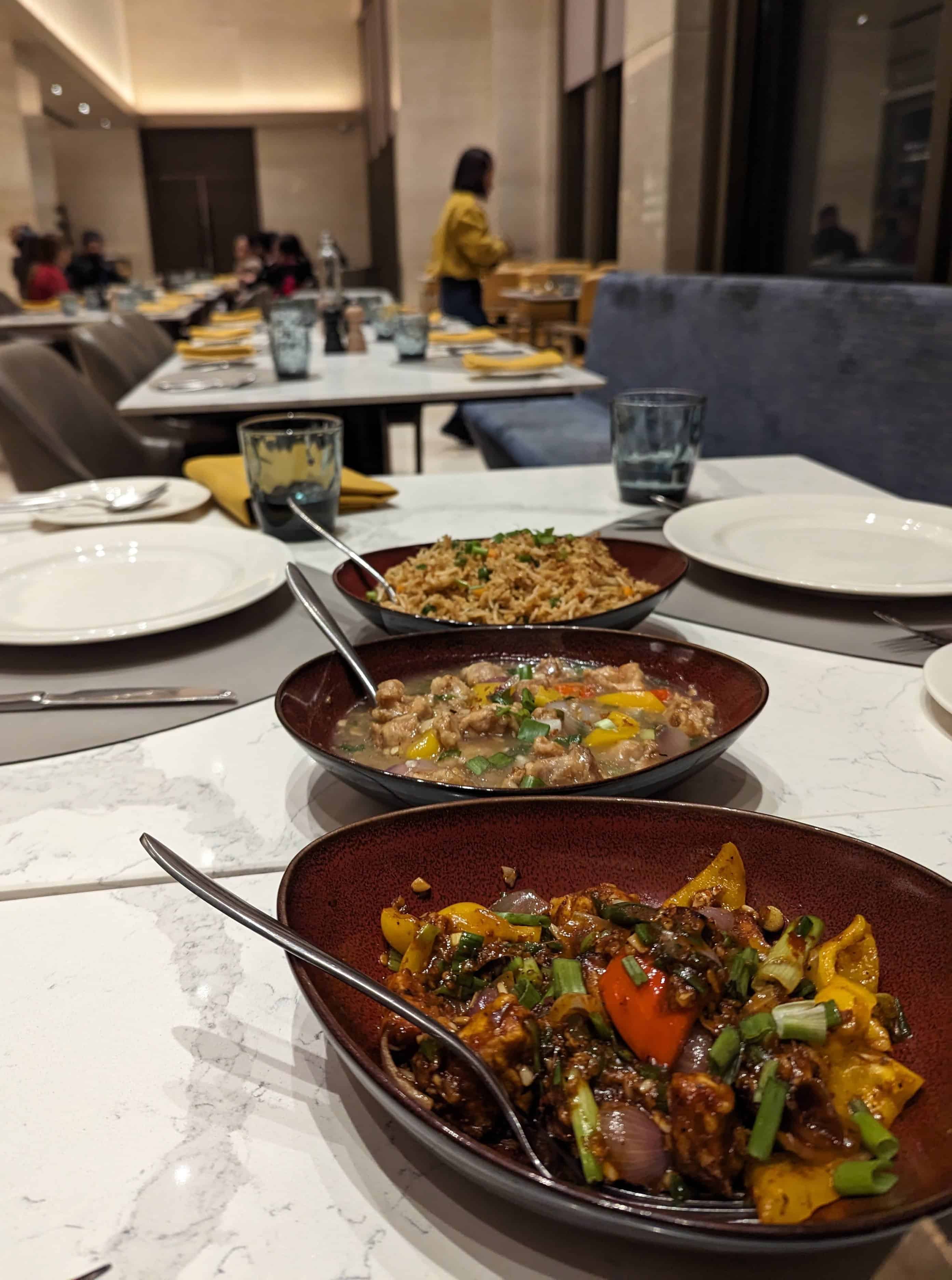 Three share dishes with a mix of Asian food on a white table at Spectra restaurant in Shillong.