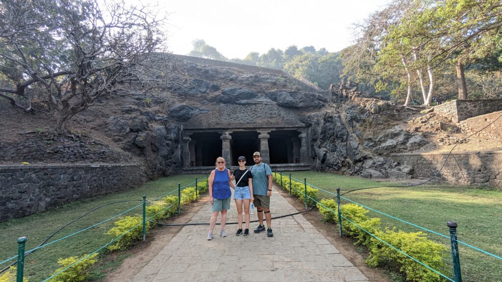 Three people standing in front of Elephanta caves, a top thing to do in Mumbai