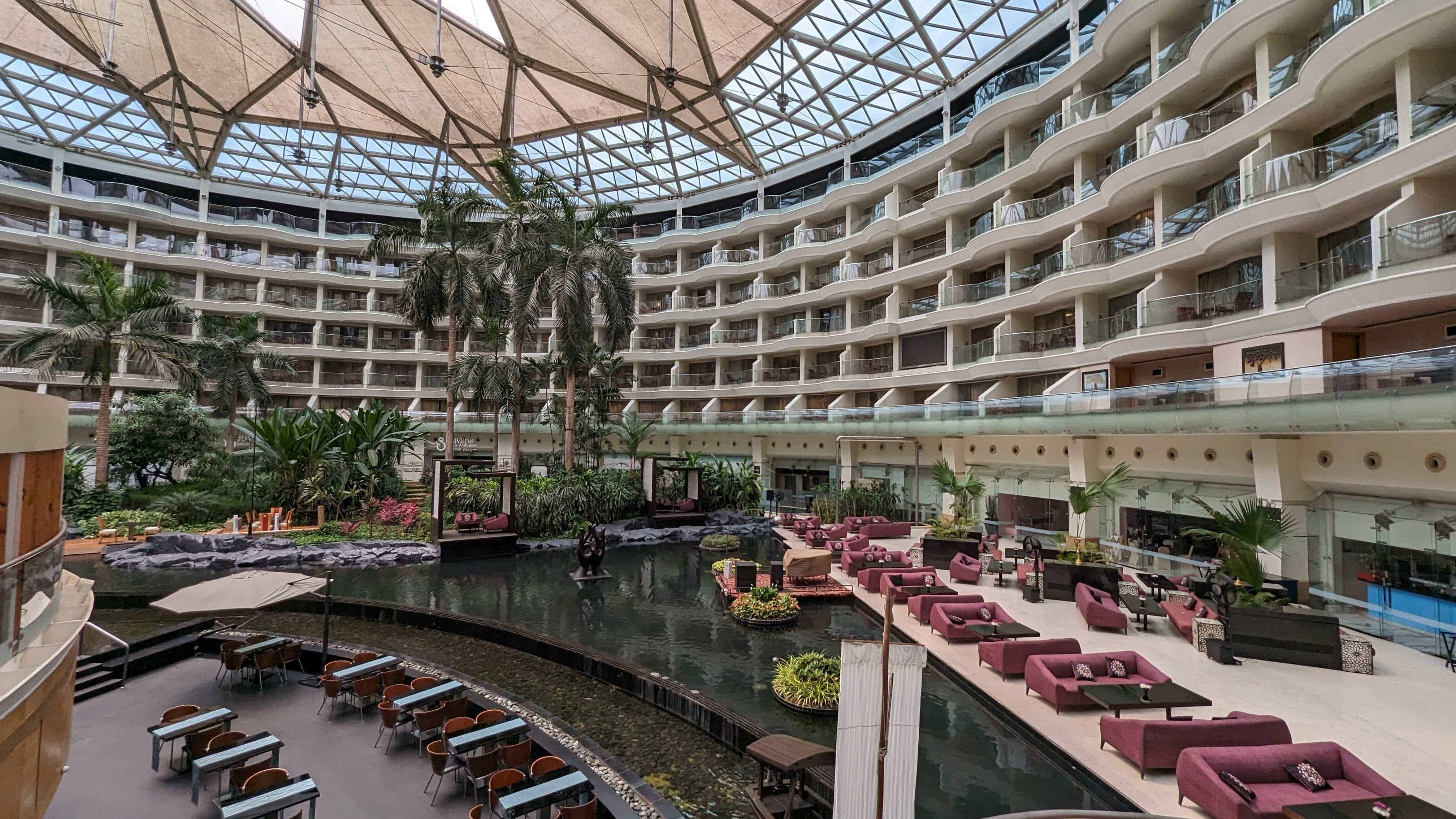 Inside Hotel Sahara Star with a view of the rooms in the background and the lounge, restaurant, and fountain in the atrium. 