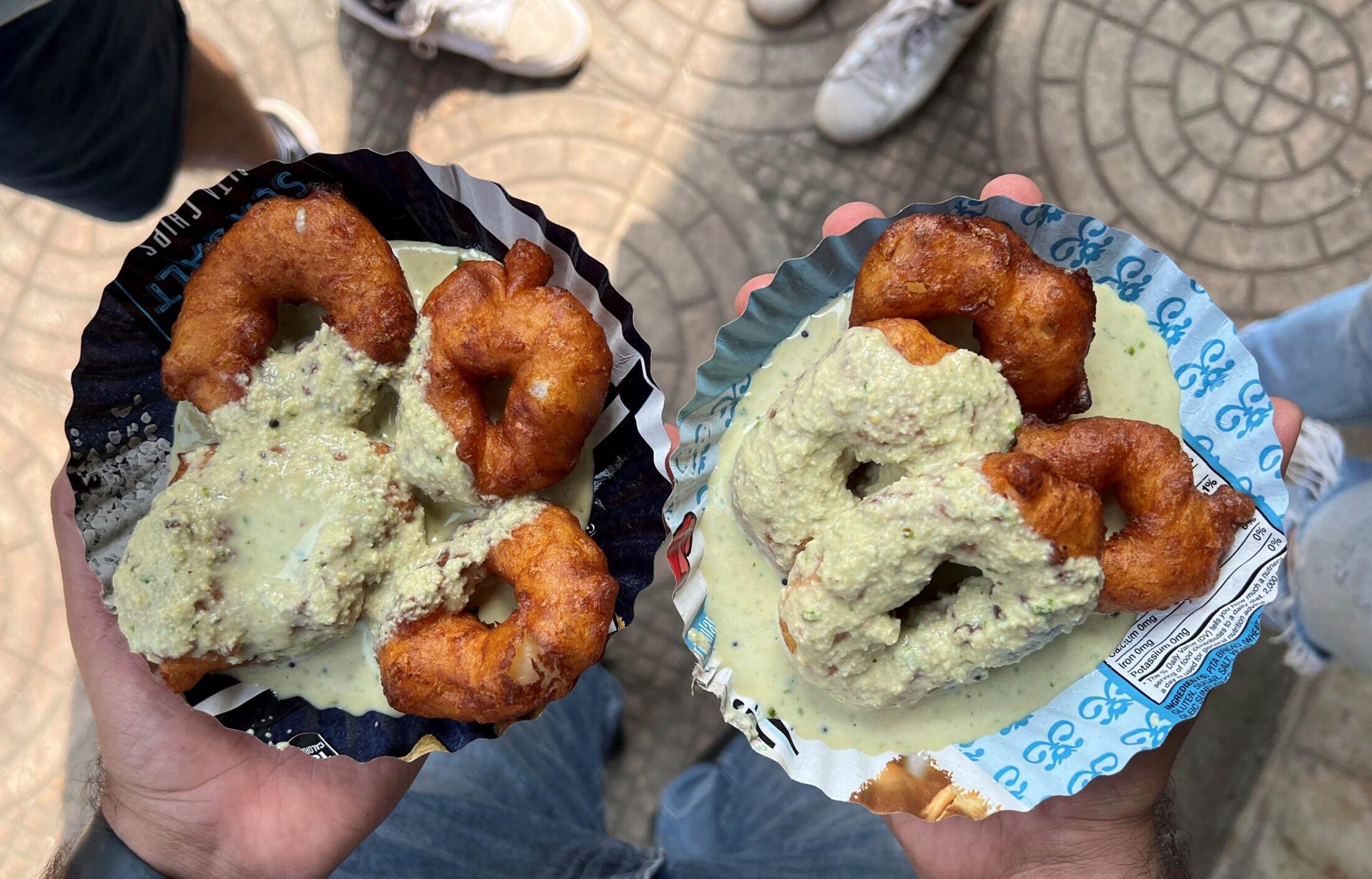 An overhead view of two plates of vadas with curry sauce on the street in Mumbai