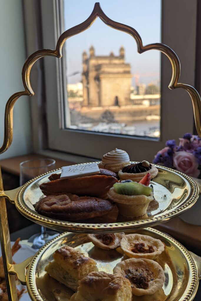 High tea served in a tiered tray sitting on window with a view of the Gateway India. Taken at Taj Mahal Palace Sea Lounge.