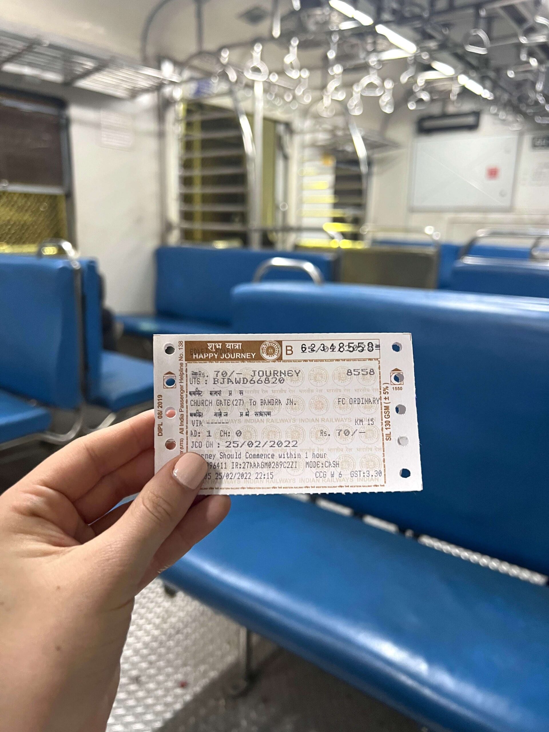 Girl's hand holding a local train ticket in an empty train car on a Mumbai Local Train.