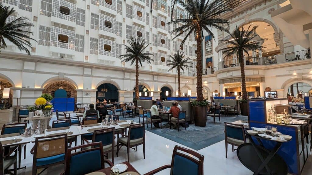 Inside the ITC Maratha near Mumbai Airport. Restaurant with tables and chairs in the middle of the hotel with the hallways to the rooms visible through lattice above.