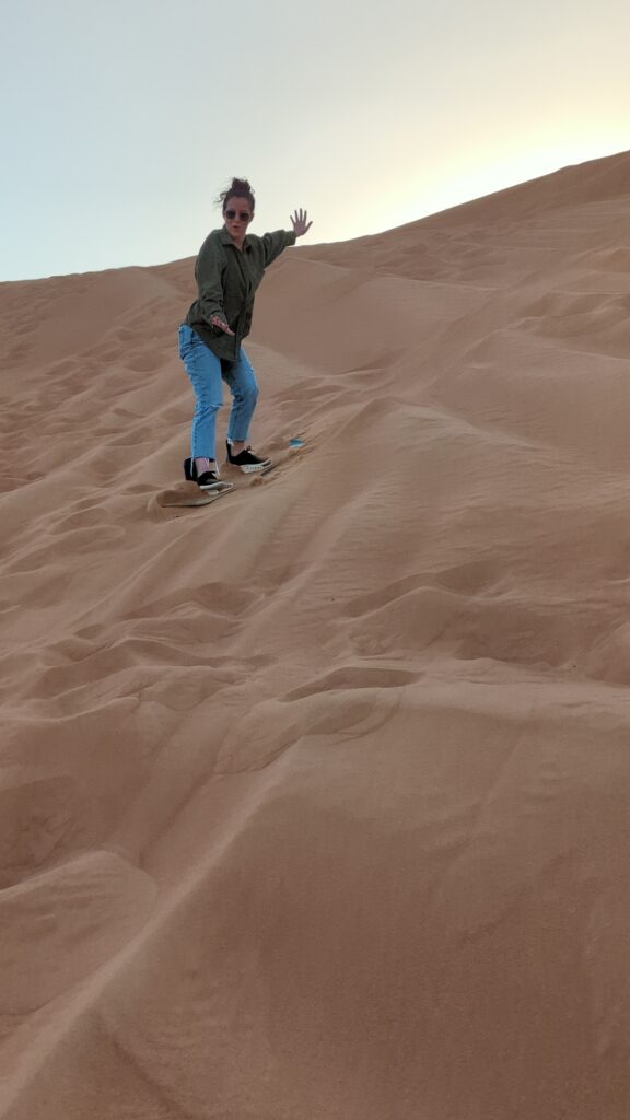 Girl sand boarding in the dunes outside of Dubai.