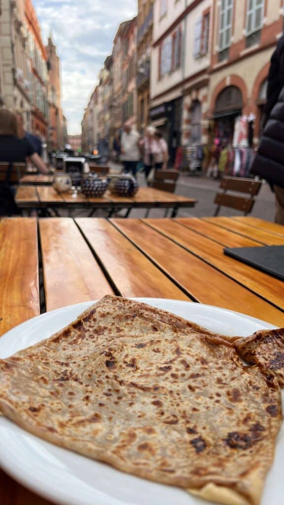 Close up of caramel crepe on a wooden table on the street of Toulouse.