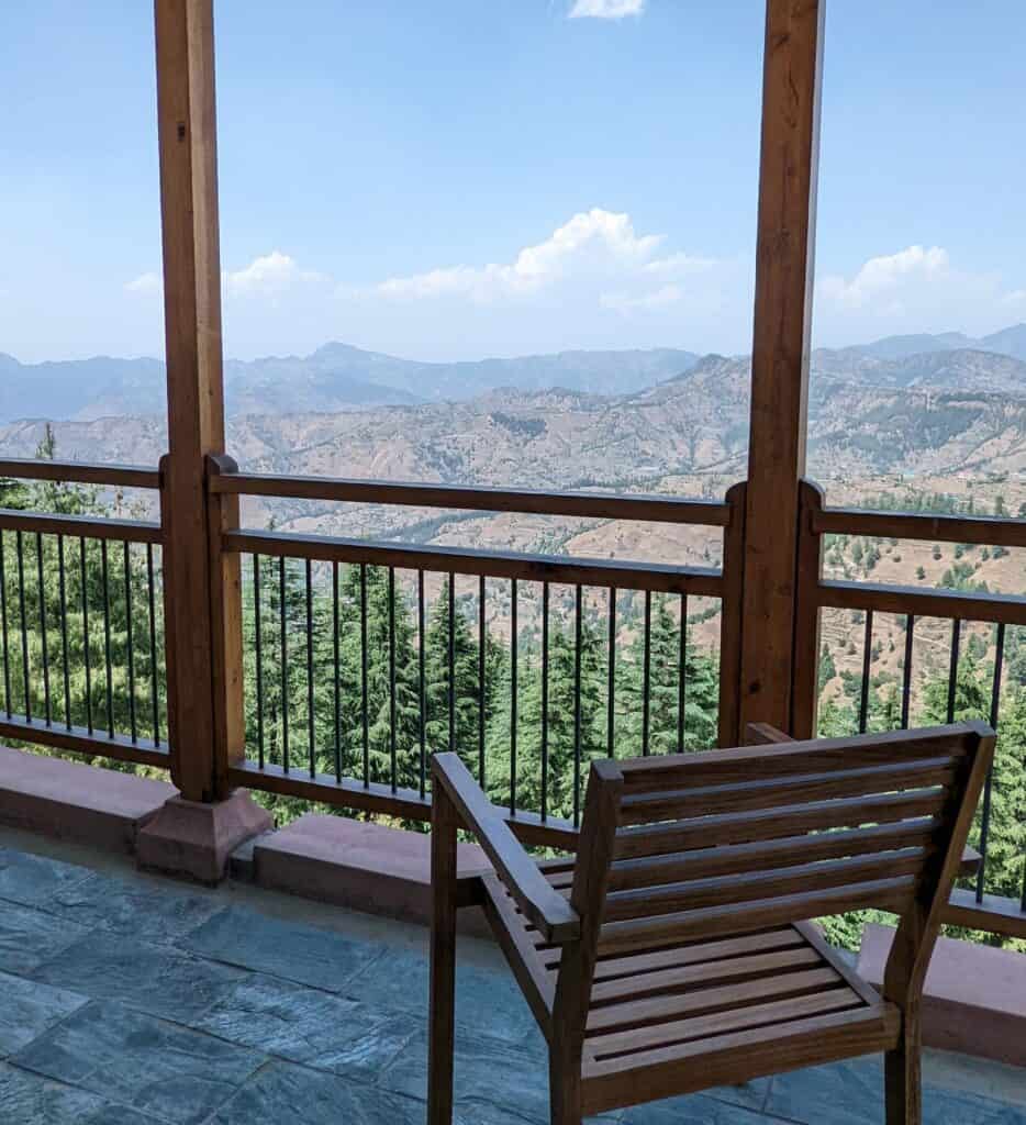 View from balcony of a room at Taj Theog with an empty chair and the Himalaya mountain peaks in the back.