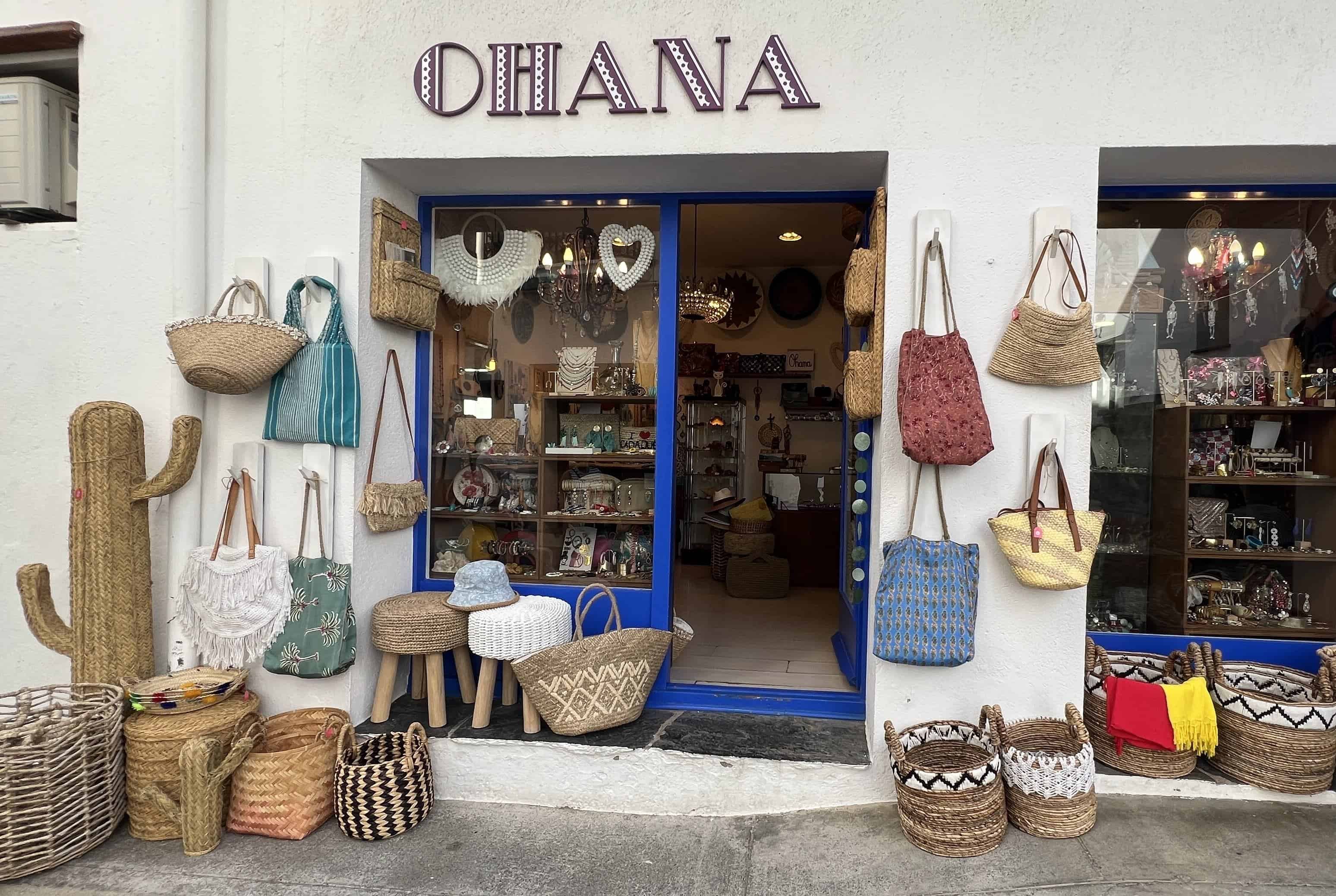 Whitewashed storefront in old town Cadaques with Ohana sign and lots of woven bags on display.