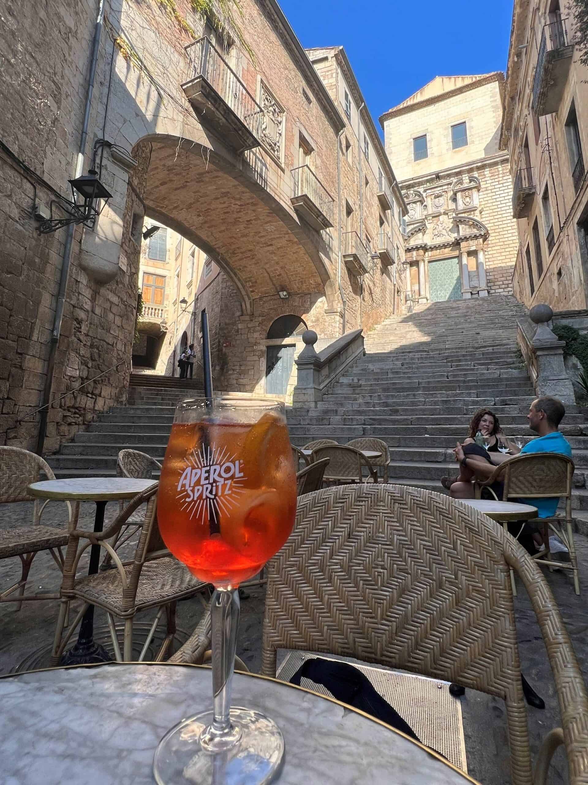 Close up of an aperol spritz sitting on a small marble table on the terrace of Cafe Bistrot in the center of old town in Girona.