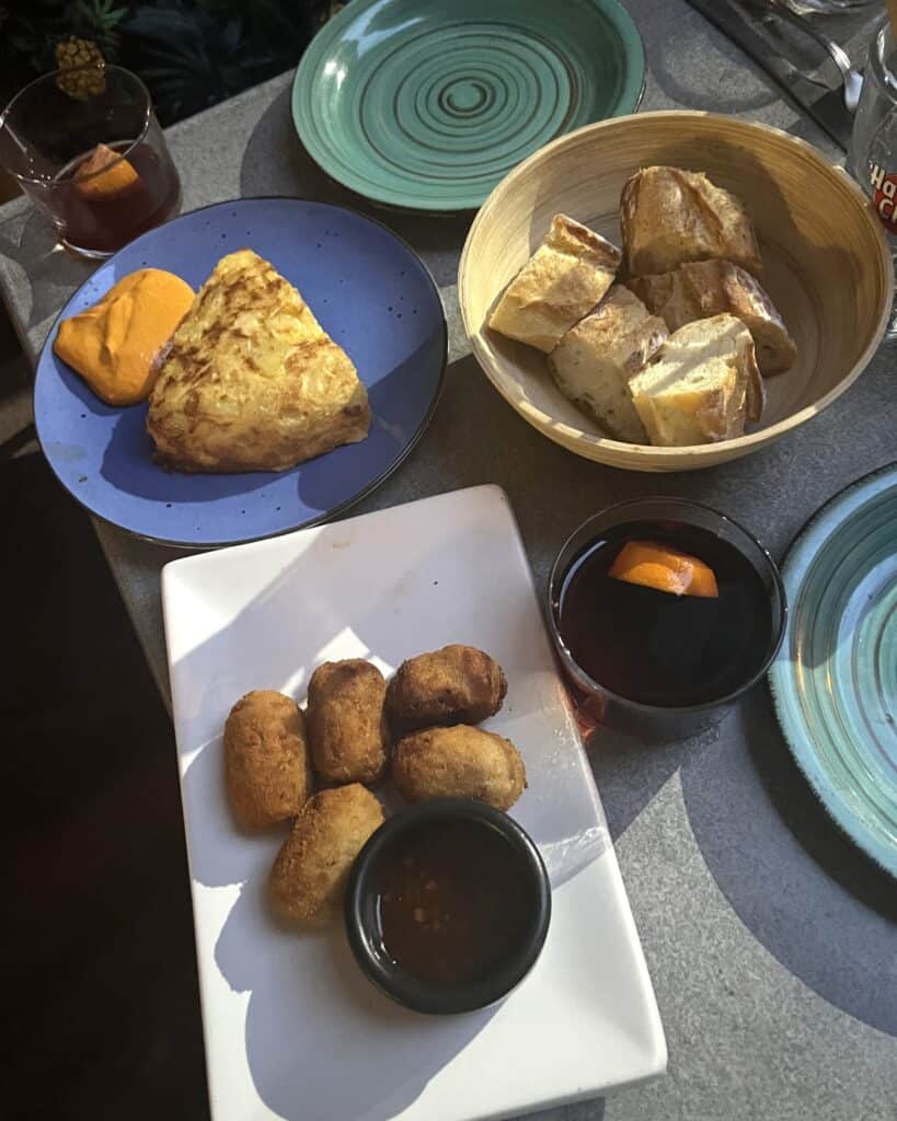 Overhead view of small plates with croquettes, bread, a tortilla, and two glasses of sangria at Paco restaurant in Collioure, France.