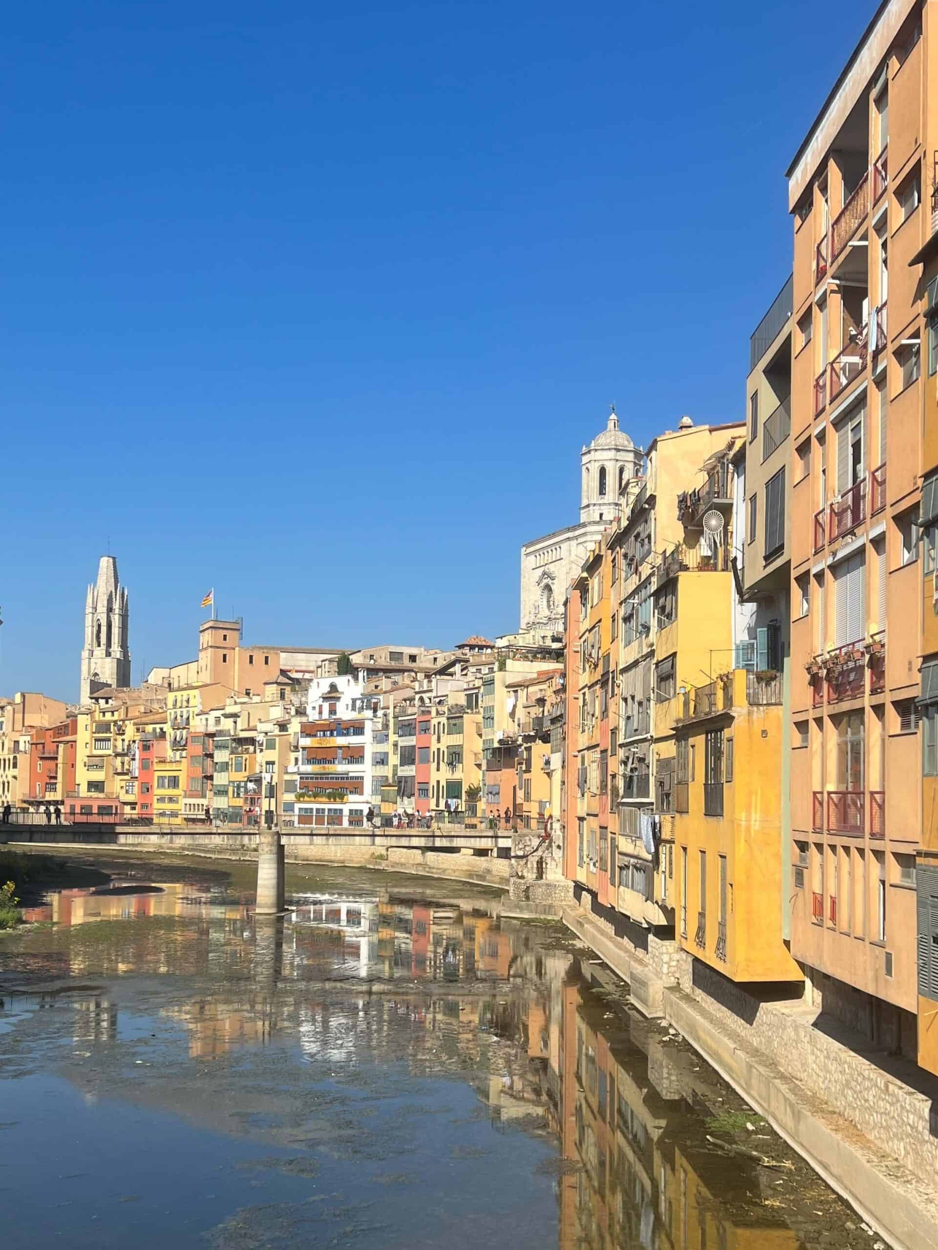 Colorful houses reflecting from the shore on the River Onyar in Girona, Spain.