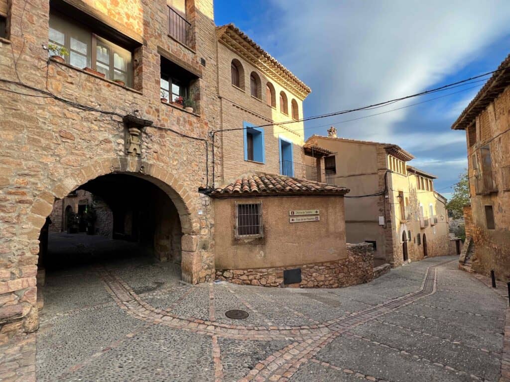 Arched stone Roman gateway and cobblestone road that leads into the village of Alquezar. 