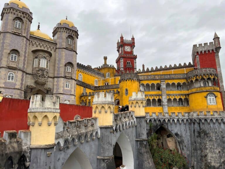 Pena Palace exterior view with purple, red, yellow turrets and terraces making it look like a fairytale castle.