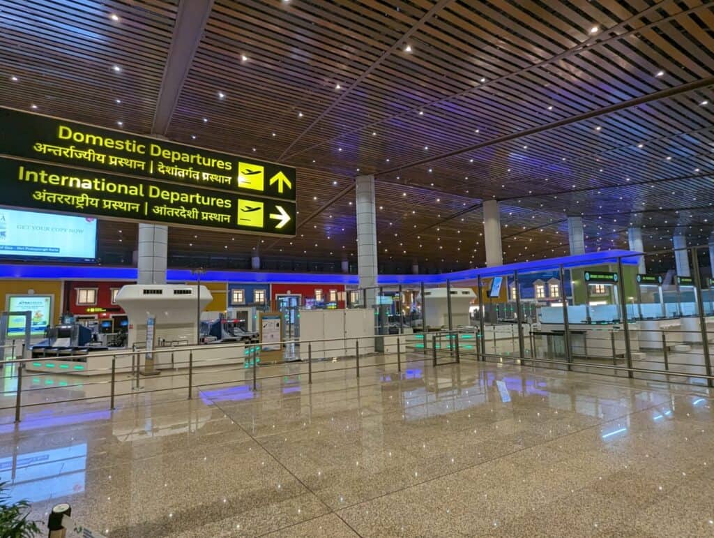 Empty departure hall at Mopa Airport in Goa with signs for international and domestic departures.