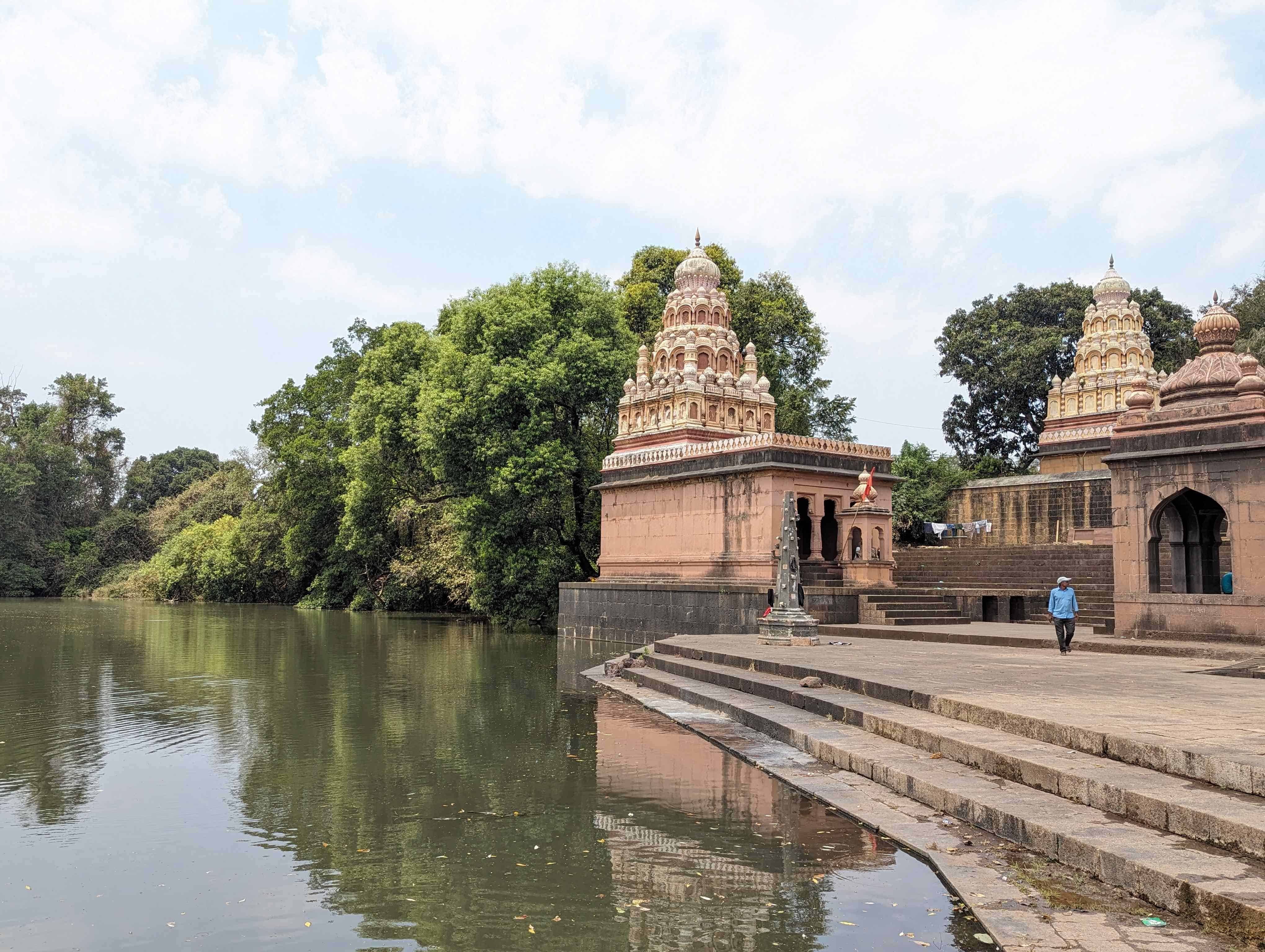 View of Nana Fadnavis Wada Temple along the river in Wai, India with green trees in the background.