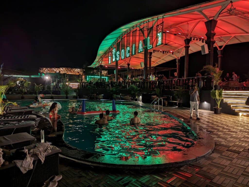 Nightime view of the pool at antisocial in Goa with colorful lighting and people chilling the water.