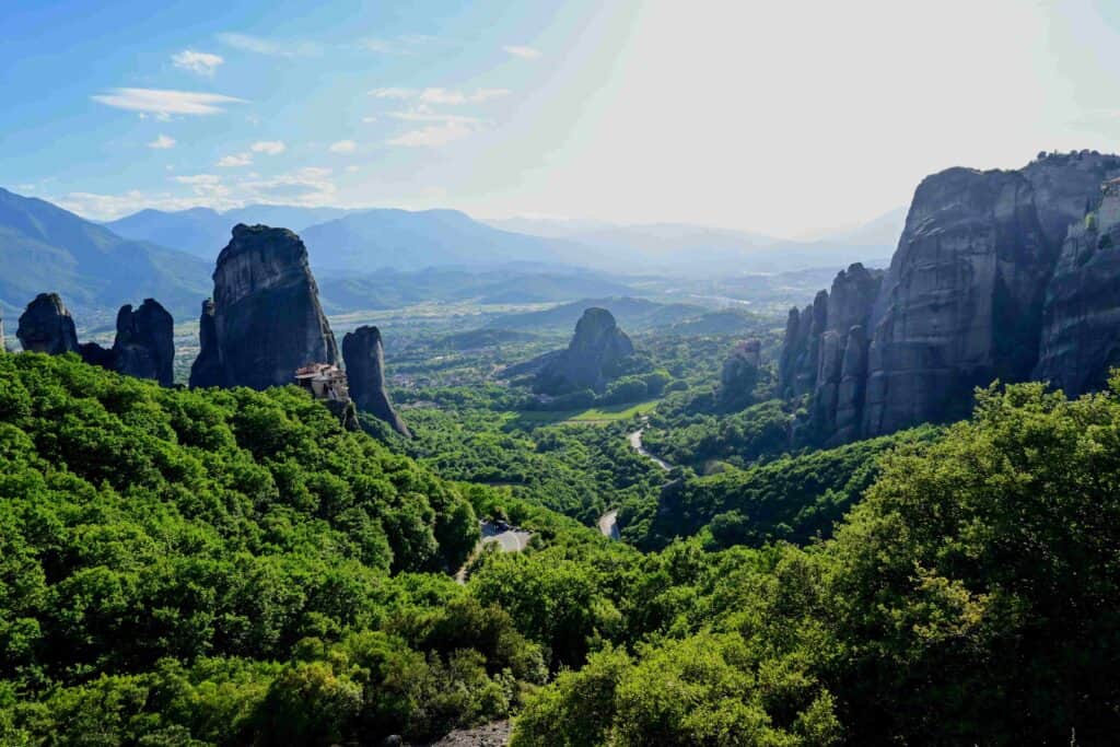 View of Meteora Greece from lookout point near Monasteries, showing the dramatic rock formations towering over the green valley of the town.