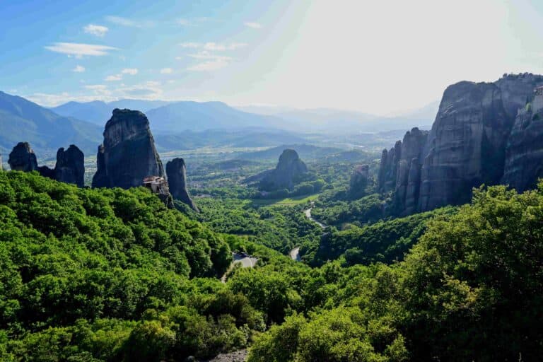 View of Meteora Greece from lookout point near Monasteries, showing the dramatic rock formations towering over the green valley of the town.