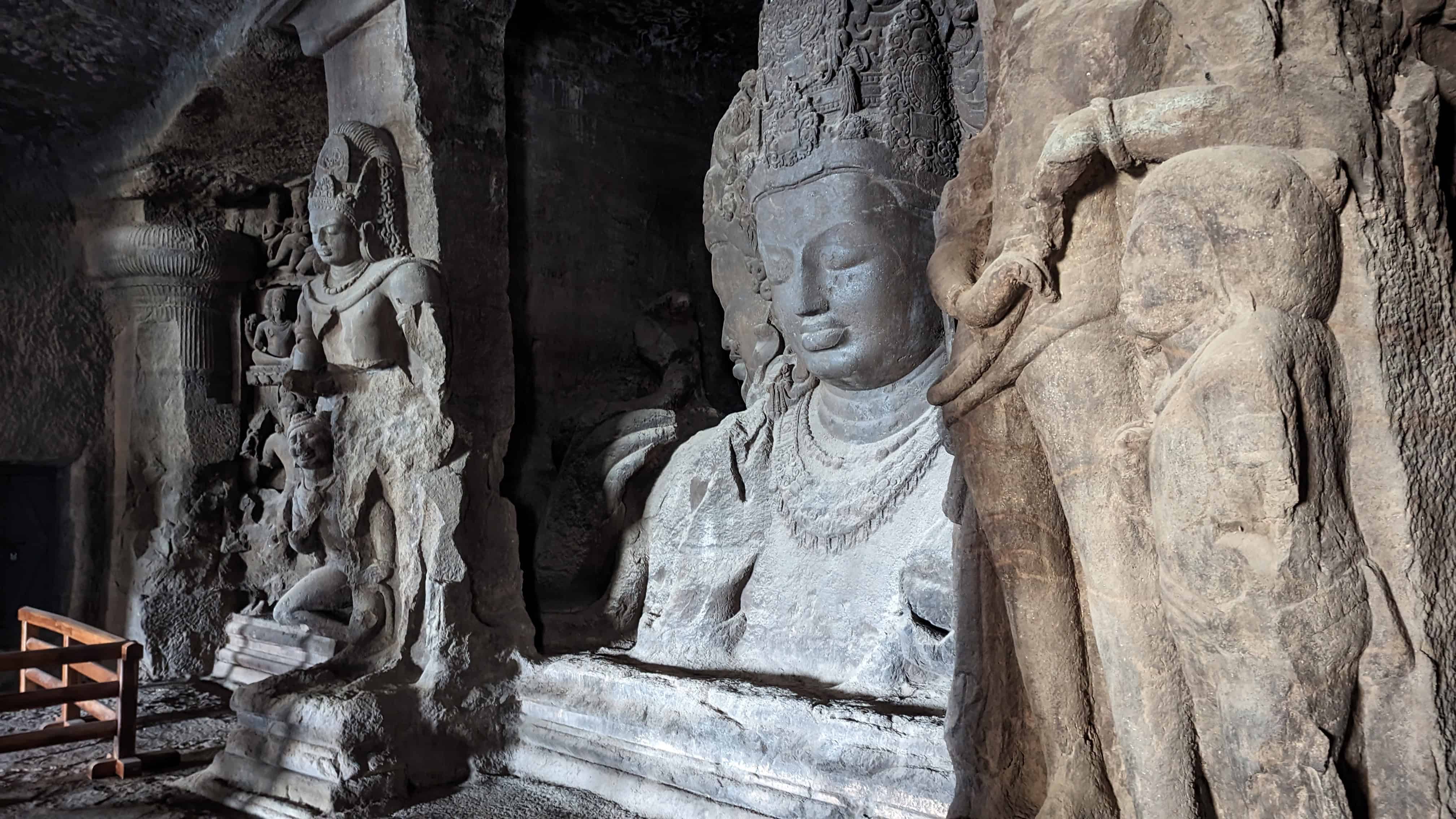 Sculptures of Buddha in the Elephanta Caves near Mumbai. There are three sculptures in the picture carved directly into basalt rock inside a cave. The sculptures are extremely intricate. 