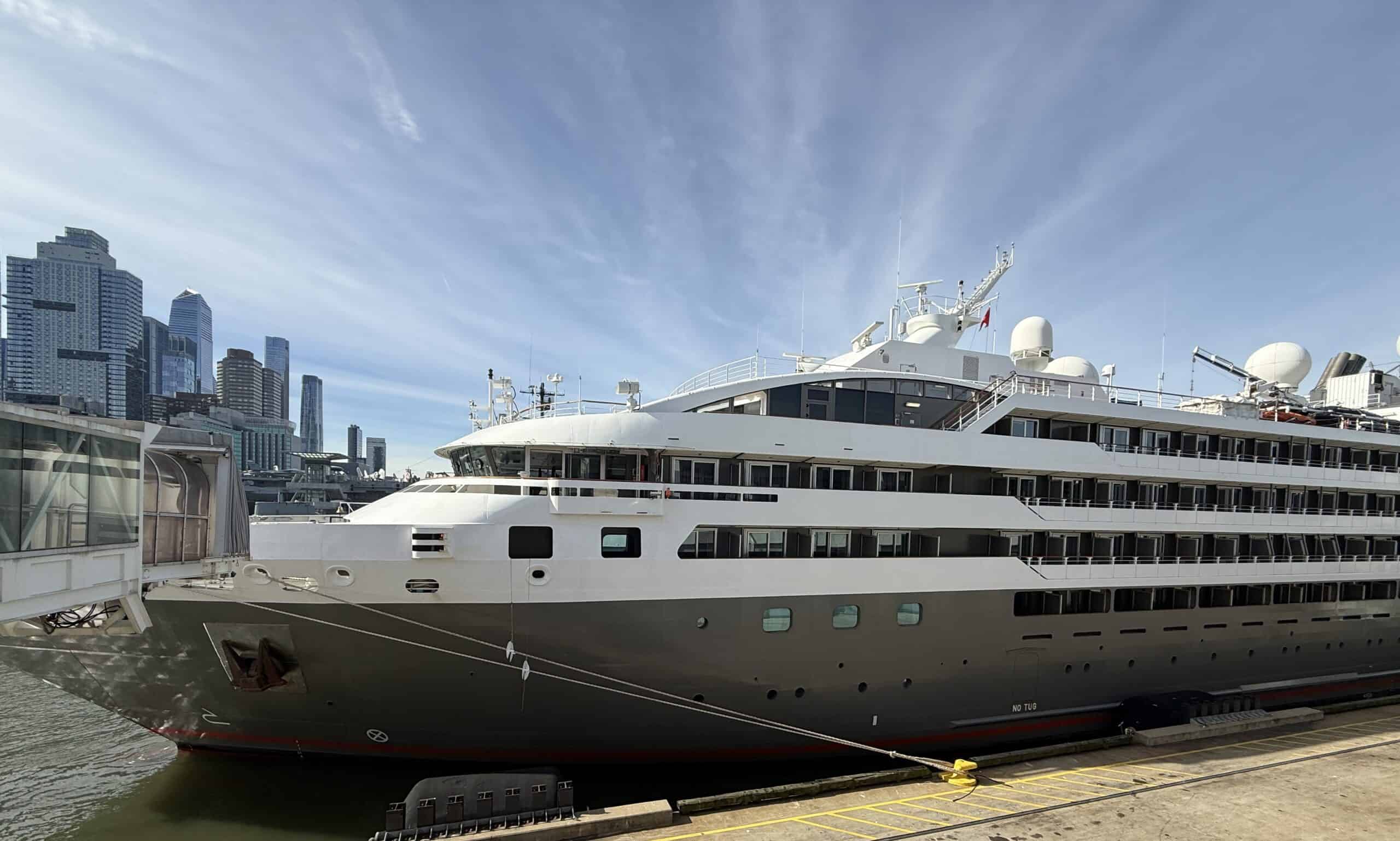 Ponant’s L’Austral cruise ship docked in Manhattan, with balcony staterooms and the New York City skyline in view.