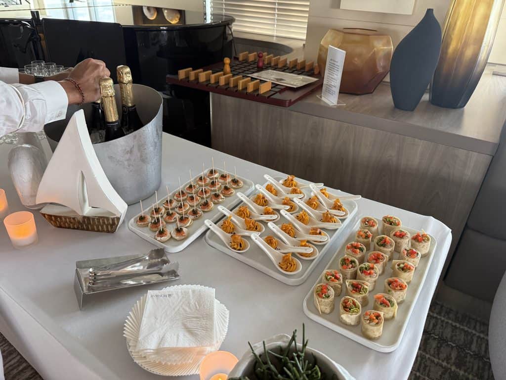 Canapés, appetizers in ceramic spoons and vegetable wraps displayed beside chilled champagne aboard Ponant’s L’Austral.